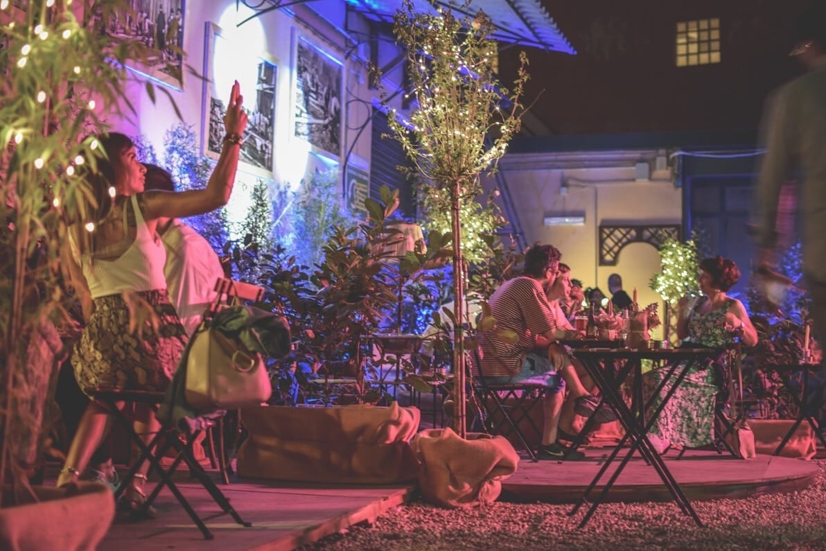 Il cortile della falegnameria Legnami Blasi di sera, trasformato in cocktail bar, con persone sedute ai tavoli