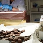 Peyrano: nel laboratorio del cioccolato di Peyrano, con cioccolatini in primo piano e mani al lavoro sullo sfondo