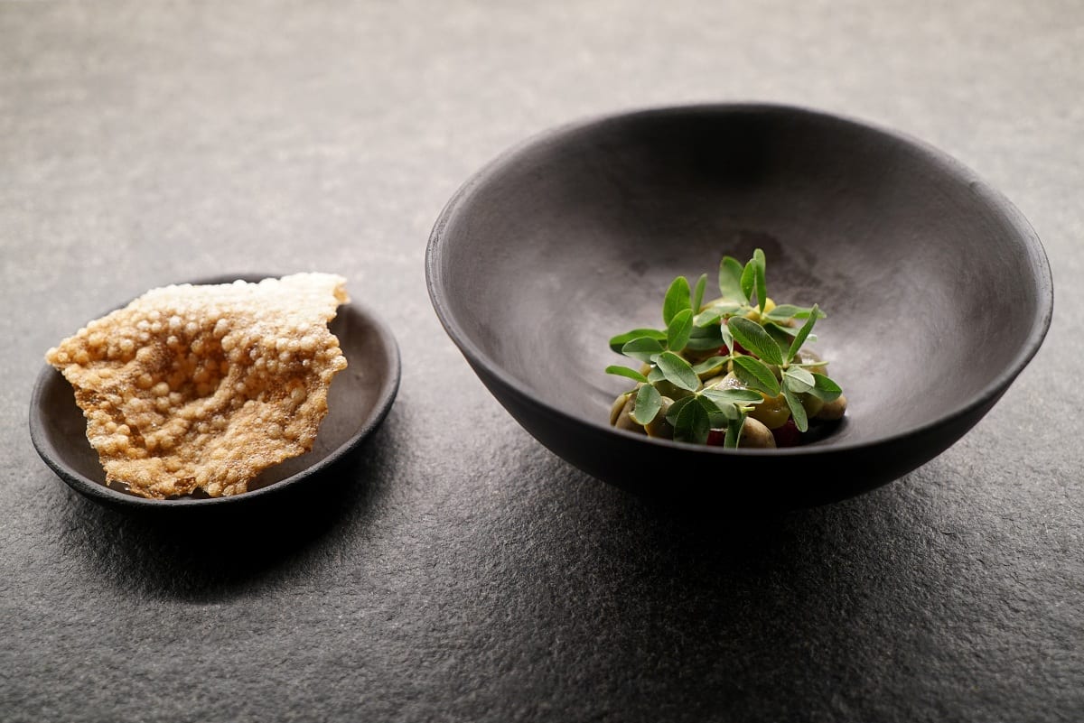 Le olive all'ascolana di Retrobottega a Roma, con ciotola nera e piattino con cialda croccante su tavolo nero