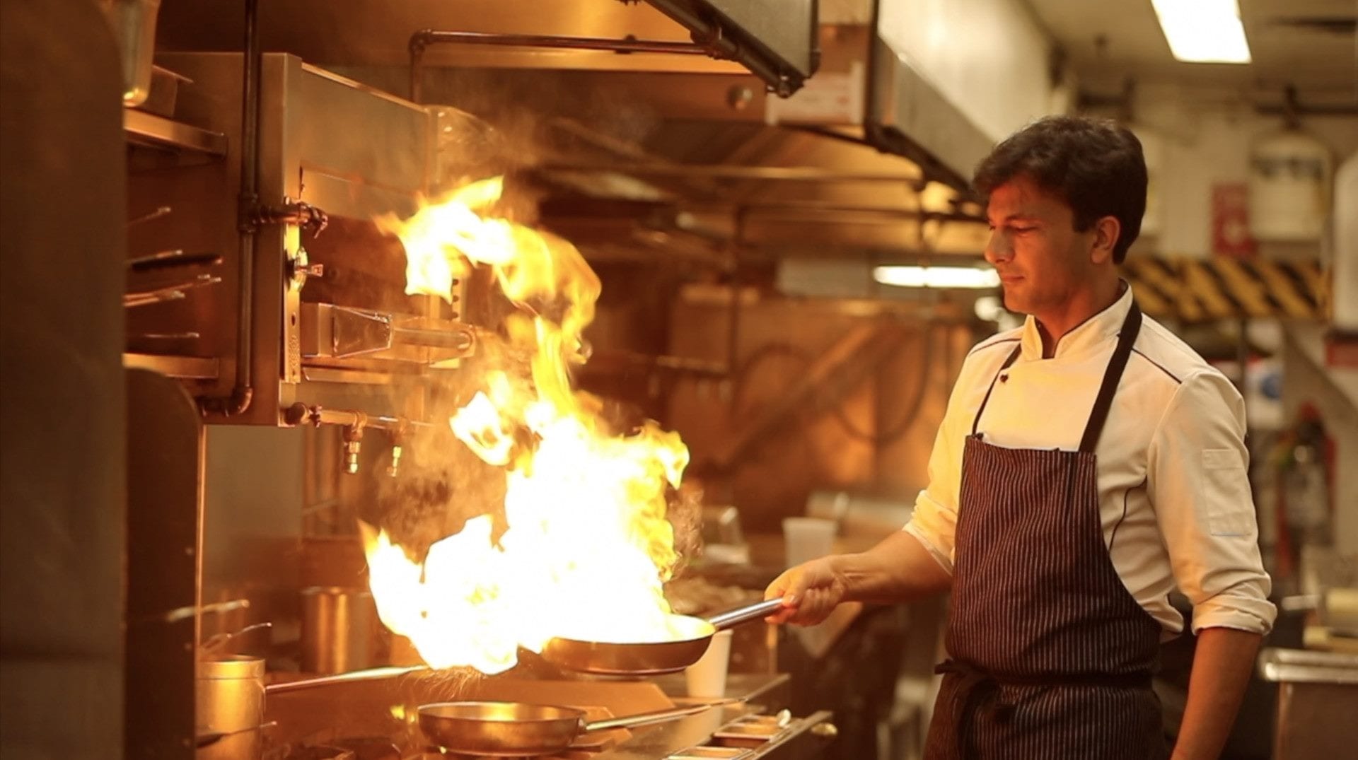 Una scena del film Buried Seeds con il cuoco che fiammeggia una padella in cucina