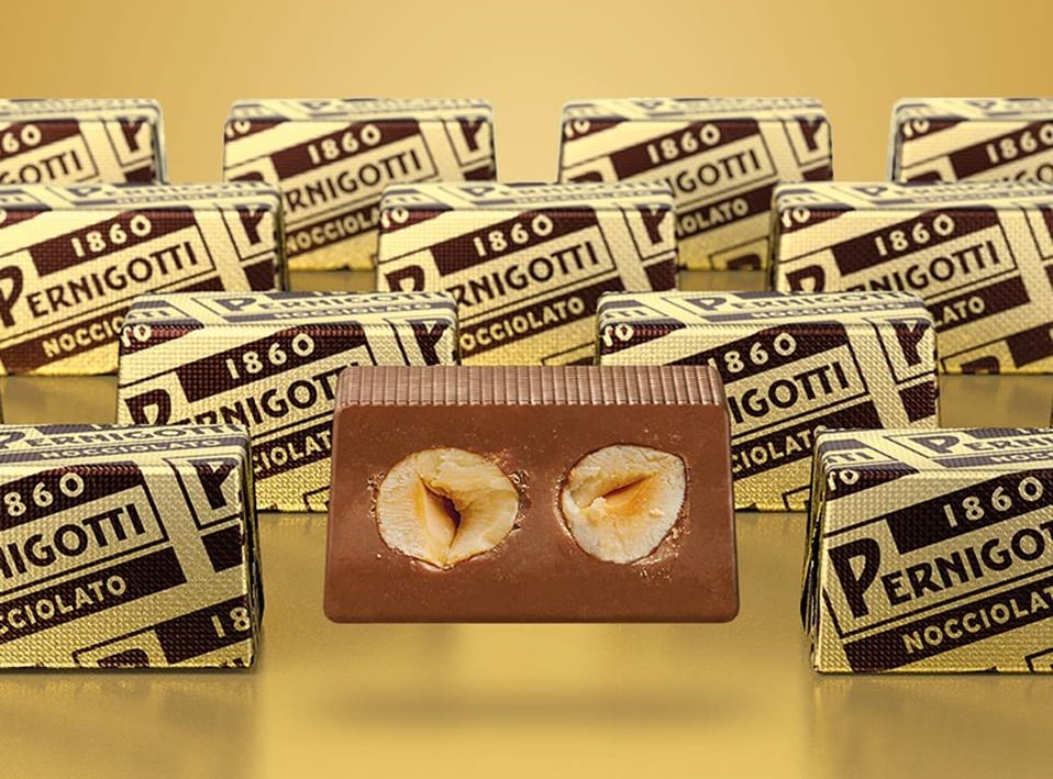 Cioccolatini con nocciole di Pernigotti, uno al centro senza incarto, in sezione, gli altri con incarto dorato