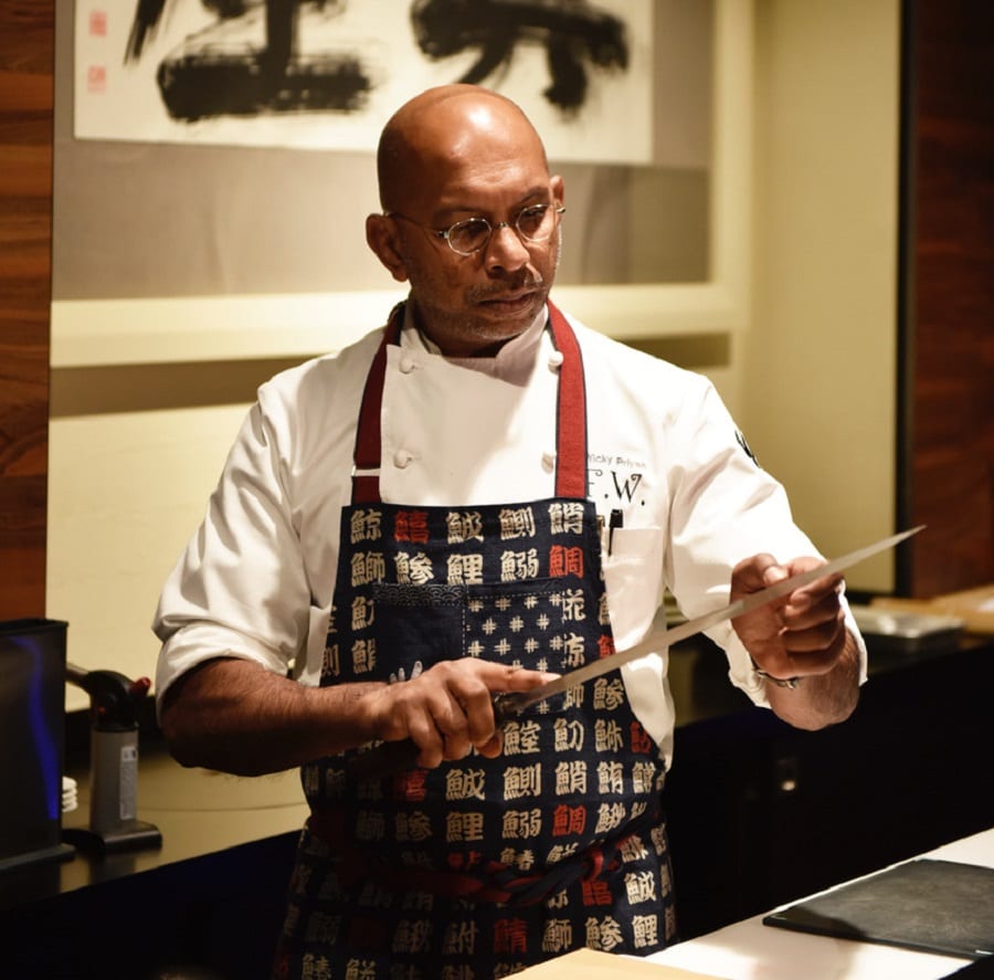 Chef Wicky Priyan dietro al kaiten, con un coltello da sashimi