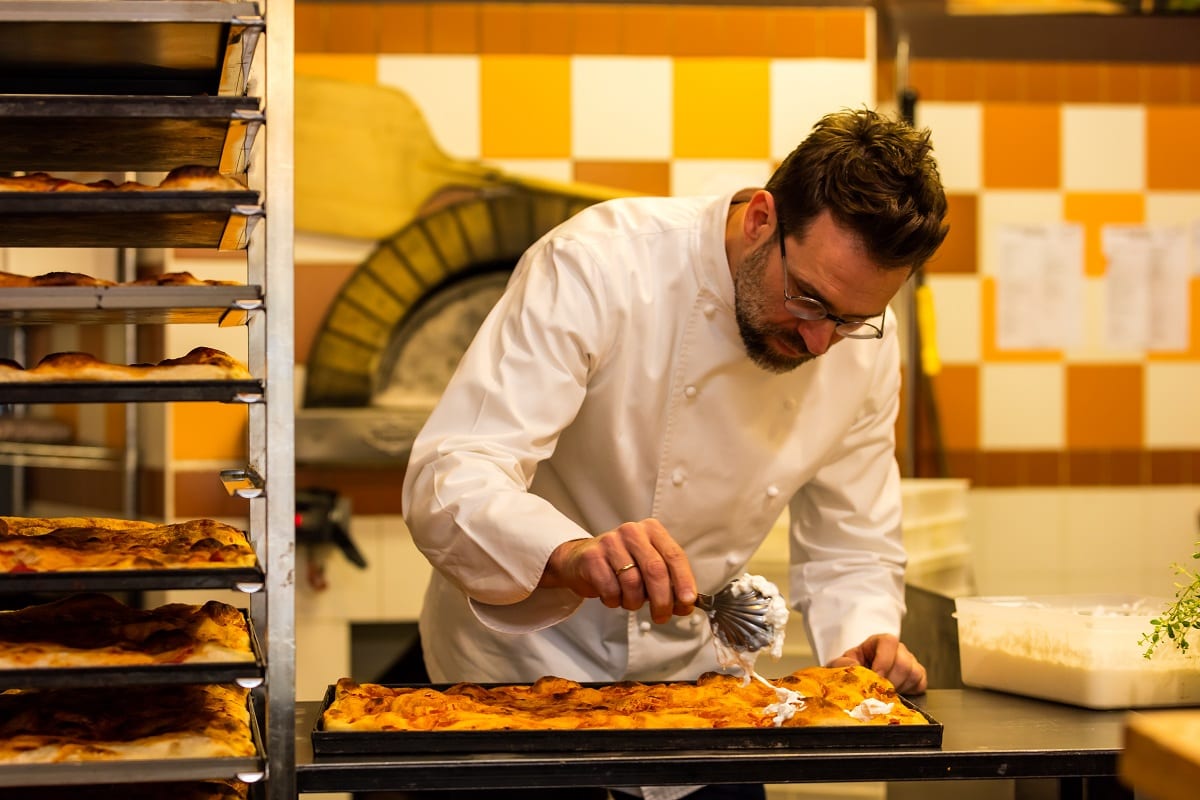 Renato Bosco in laboratorio mentre termina una teglia di pizza Doppio Crunch