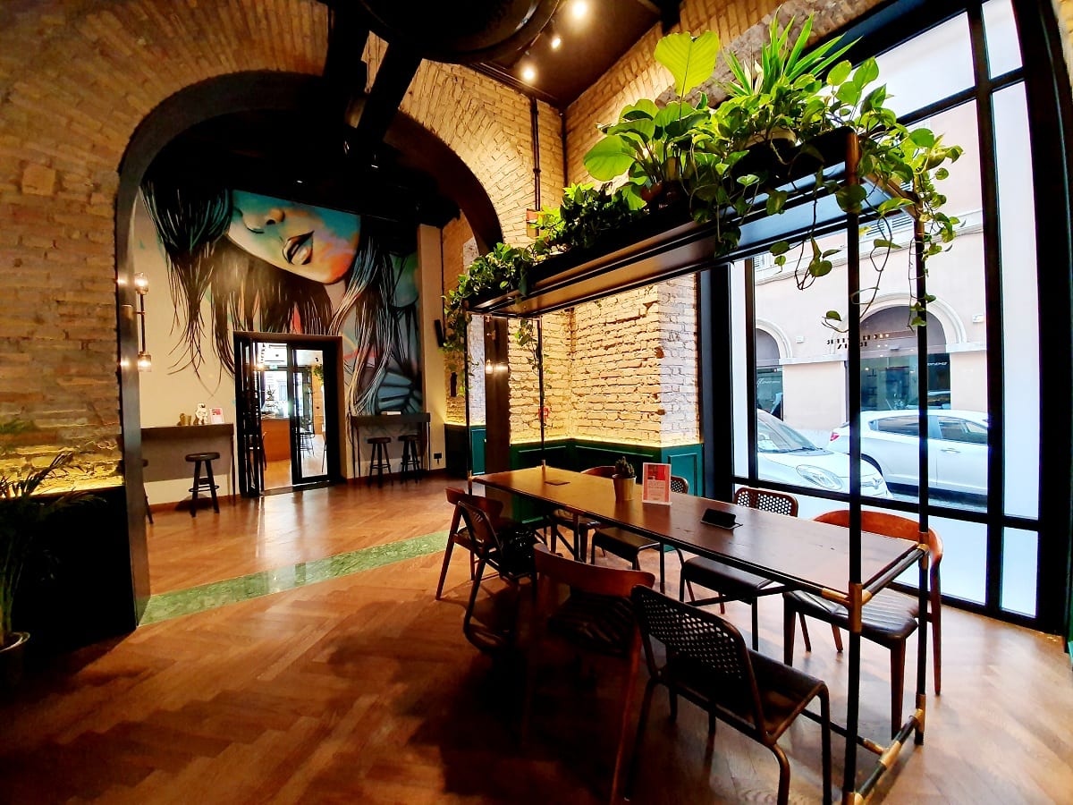 Il bar dell'Hotel Chapter, con archi in mattoncini, murale, piante sospese