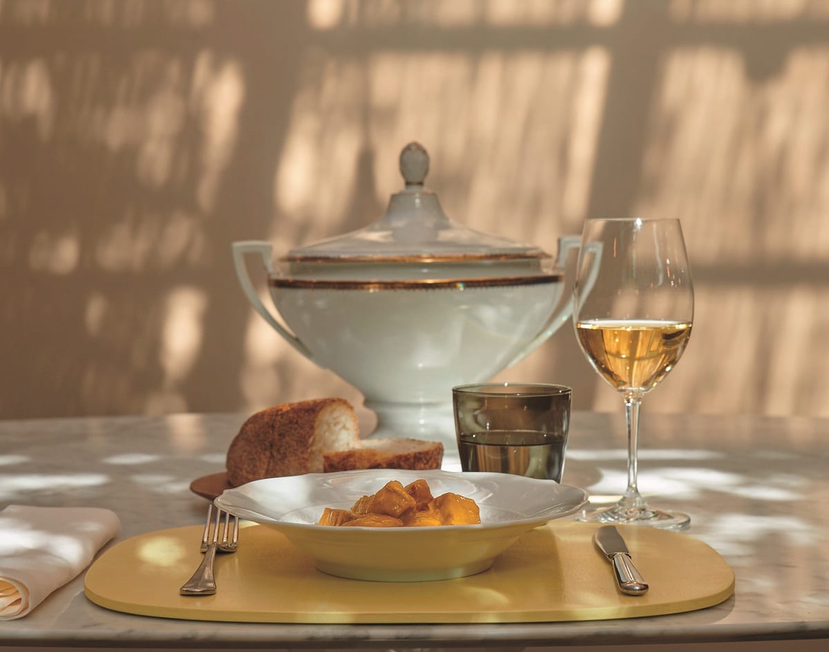 Zuppa di totani di Niko Romito, servita al piatto, con calice di vino e zuppiera in porcellana al tavolo