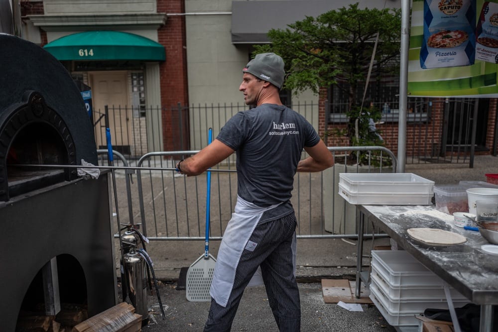 Luca Arrigoni inforna la pizza in un forno su strada, durante un festival gastronomico a New York