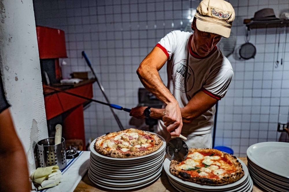 Luca Arrigoni taglia in spicchi una pizza margherita da Sottocasa
