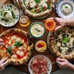 La tavola di Gloria del gruppo Big mamma, presa dall'alto, con pizze e sfizi italiani da condividere