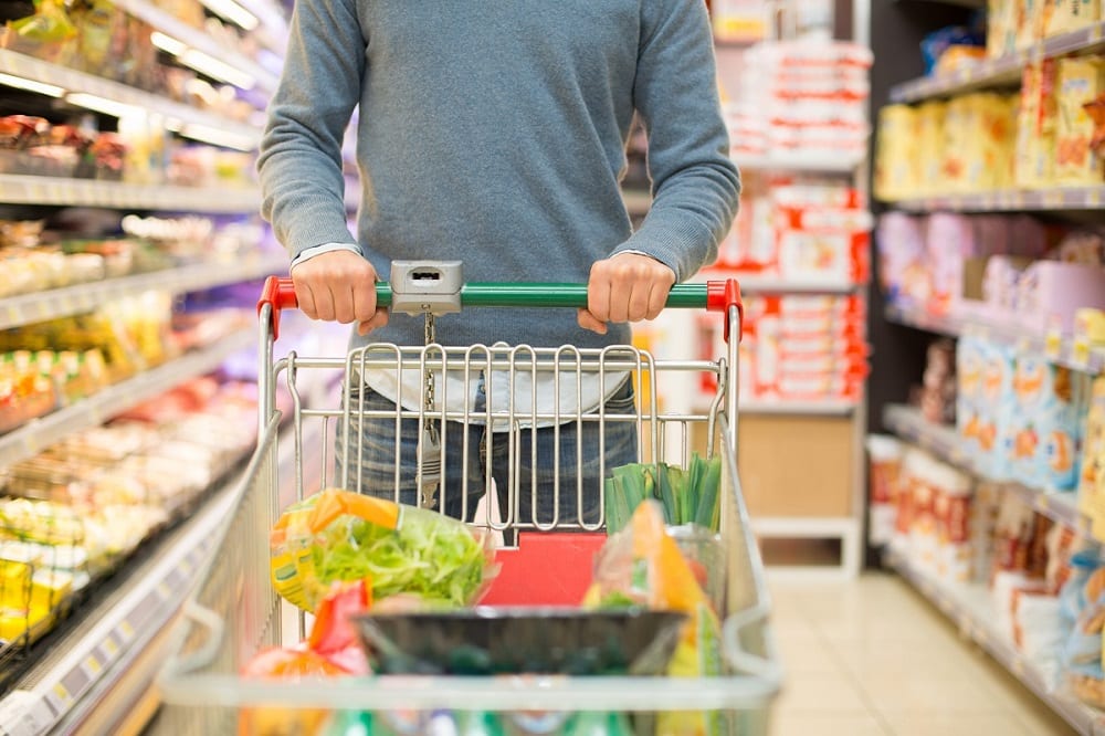Un uomo si muove col carrello tra gli scaffali del supermercato