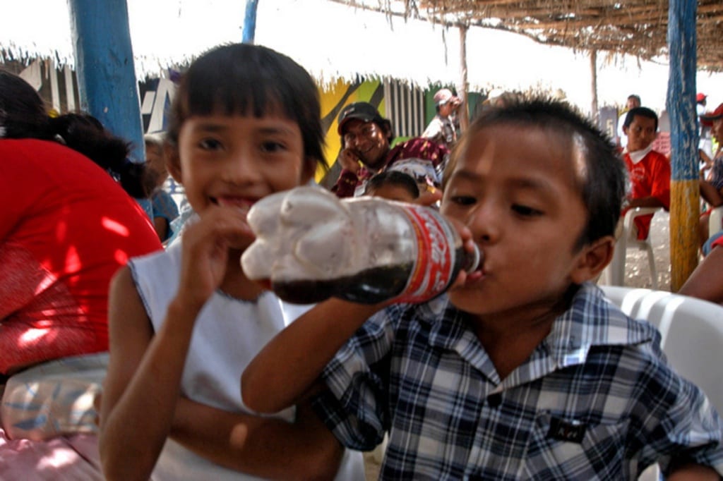 Bambini messicani bevono coca cola dalla bottiglia
