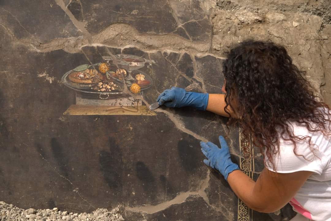 Un'archeologa al lavoro a Pompei durante il ritrovamento dell'affresco della pizza di 2000 anni fa