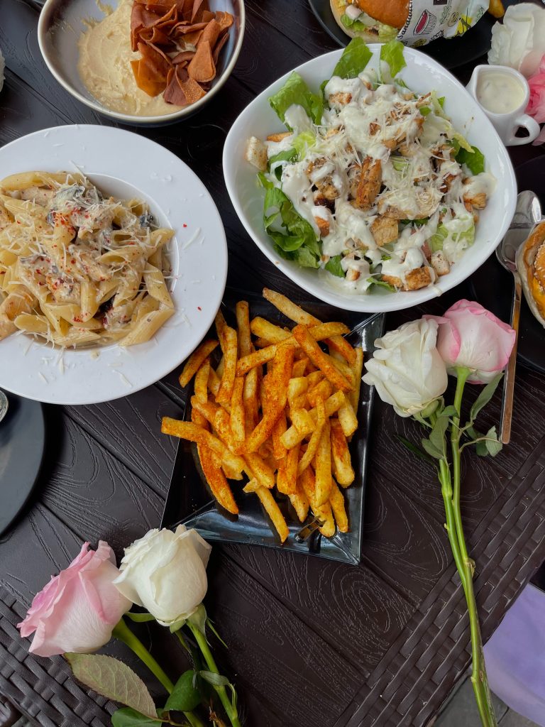 Una Caesar salad, un piatto di penne e le immancabili patatine fritte