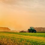 a tractor in a field plows the ground at dawn, sowing grain, sunset, sunrise. High quality photo