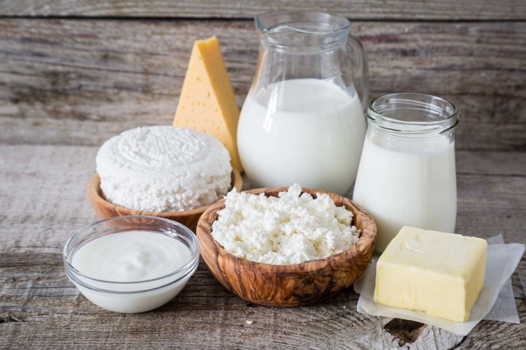 |Kefir grains on a wooden spoon above a jar of milk kefir|Glass jug and glass with milk on a wooden rustic background.|||