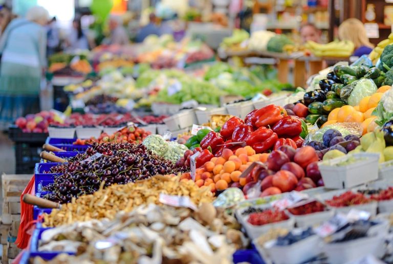 Un banco di frutta e verdura|Controllo di un'etichetta su vaschetta di fragole inquadrato con smartphone