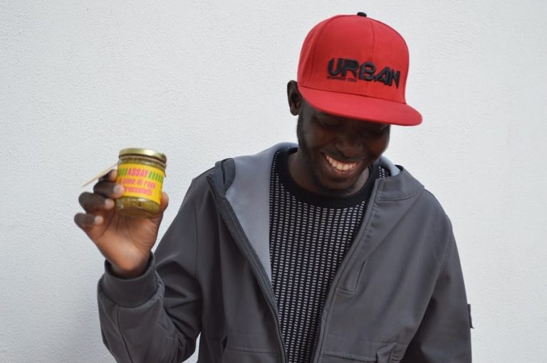 Un ragazzo africano sorride mentre mostra un barattolo di pesto Assay|||Il pesto di Assay su una fetta di pane
