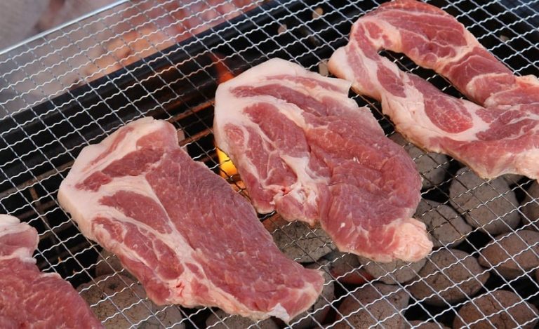 Bistecche di collo di maiale ancora crude sulla brace|carne maiale