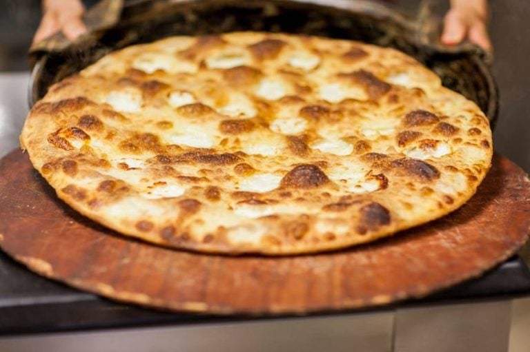 La focaccia di Recco appena sfornata su un tagliere di legno||
