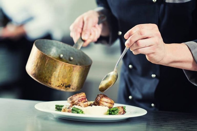 Un cuoco in divisa nera termina il piatto con la salsa presa dalla pentola|Formaggi francesi