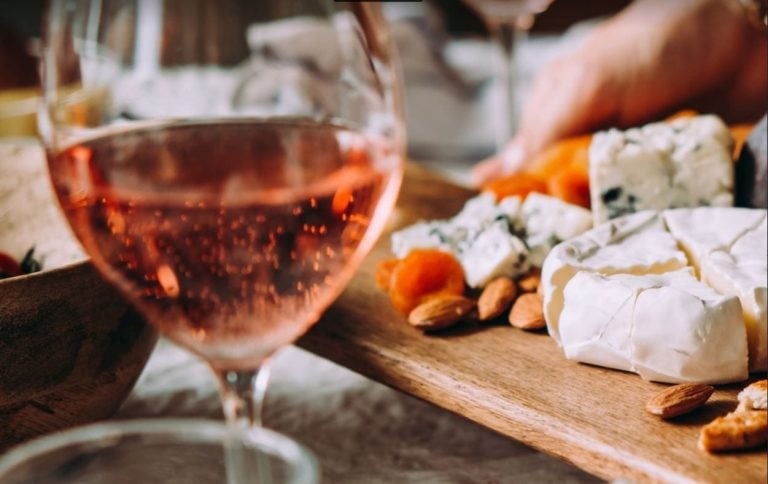 Tagliere di formaggi con calice di vino rosè