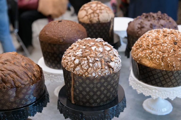 I panettoni dei Maestri del Panettone a Milano|||un panettone con copertura al cioccolato e mandorle a scaglie|Un panettone tagliato con fetta in primo piano|Un panettone tagliato a metà