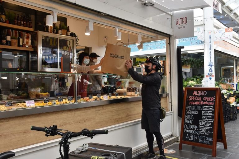Rider ritira cibo al mercato di Testaccio|Rider in bici con buste della spesa MyBanco|Una famiglia sistema la spesa ricevuta da Mybanco