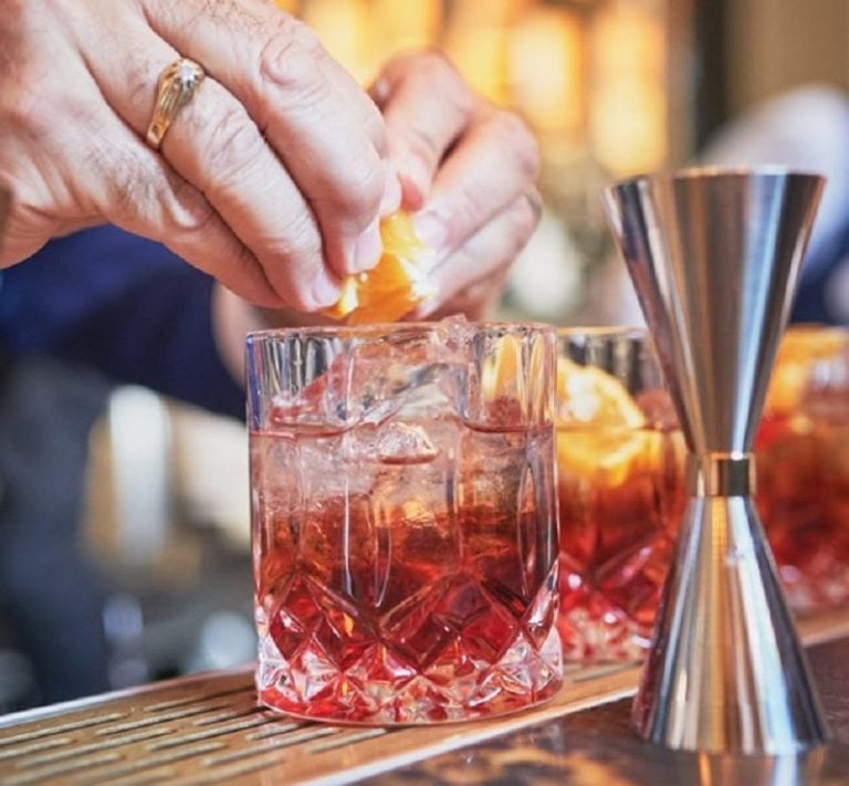 Le mani di The Maestro mentre prepara un Negroni|I protagonisti della tavola rotonda sul Negroni al Palagio di Parte Guelfa|La tavola rotonda sul Negroni: Luca Picchi mostra alcuni libri sul tema||The Maestro alla preparazione di un Negroni