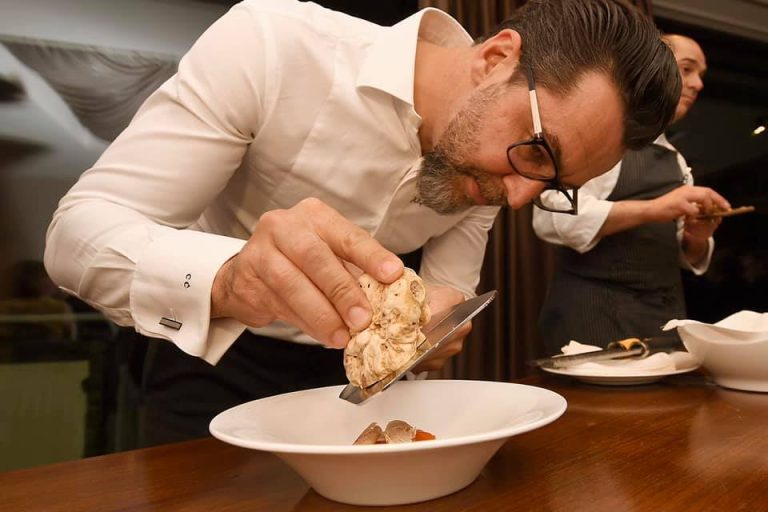 Quique Dacosta termina un piatto a base di nocciole con scaglie di tartufo bianco|Lo chef Goran Ameergad prepara un piatto a base di nocciole|Andrea Larossa prepara un taco con nocciole|Annalisa Borrello alla festa della nocciola di Villa d'Amelia|Un risotto nero con nocciole e tartufo di Quique Dacosta|Un vassoio di nocciole alla festa delle nocciole del Piemonte