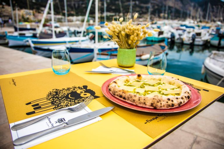 La pizza di Mauro Colagreco sul tavolo con vista sul porto vecchio di Menton di Pecora Negra|Il logo della pizzeria Pecora Negra||Festeggiamenti sul palco della World's 50 Best Restaurants per Mauro Colagreco