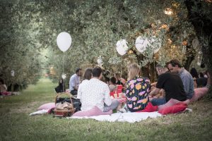 Immagine del pic nic Scamporella con i palloncini bianchi le persone sedute sul prato|Talvolta