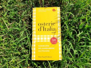 La guida Osterie d'Italia 2020 su un prato verde|La guida Osterie d'Italia 2020
