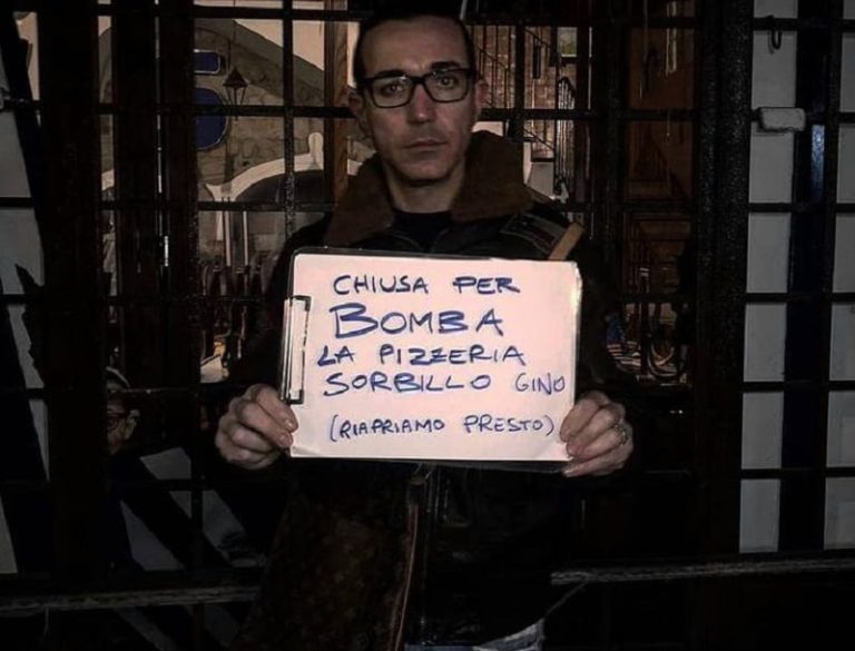 Gino Sorbillo con il cartello che denuncia l'intimidazione alla sua pizzeria di Napoli|