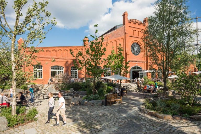 L'edificio in mattoni rossi di Stone Brewing Berlin visto dal giardino|La tap room di Stone Brewing Berlin