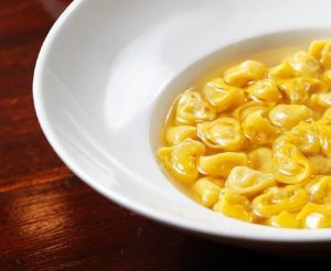 Un piatto di tortellini in brodo|La sfoglia con il ripieno porzionato per la preparazione dei tortellini