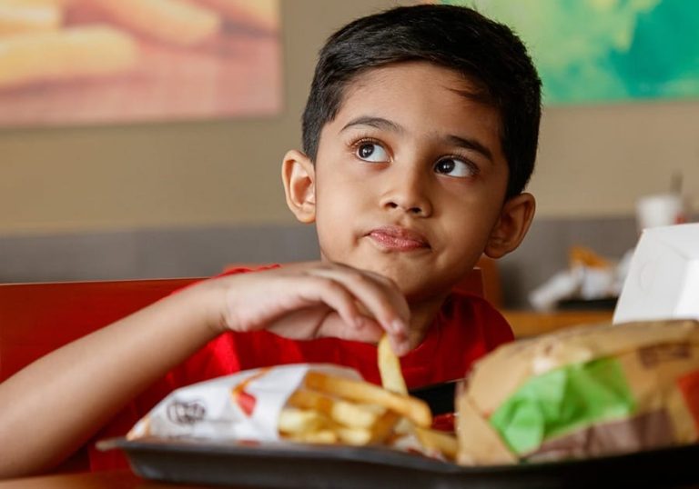 Un bambino mangia patatine e hamburger in Bangladesh||