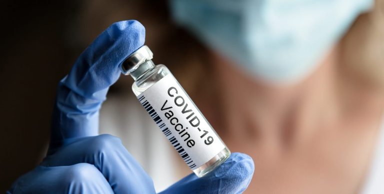 Una fiala di vaccino anti covid|Camerieri al lavoro per sterilizzare i tavoli