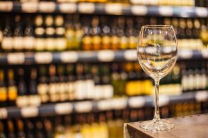 un calice di vino bianco e sullo sfondo gli scaffali