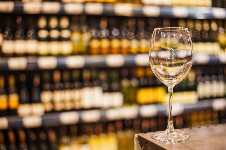 un calice di vino bianco e sullo sfondo gli scaffali
