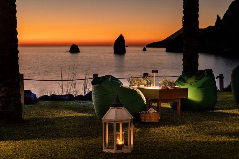 Tavola sul prato al tramonto al ristorante I Tenerumi|Servizio al tramonto a I Tenerumi|Davide Guidara|La vista sul mare delle Eolie dal giardino del Therasia