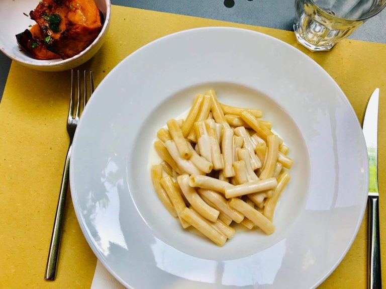 Un piatto di pasta con crema di parmigiano e ciotola di zucca al forno al tavolo della trattoria Pane e Panelle|La sala di Pane e Panelle a Bologna|Assaggi di cucina di mare al piatto da Pane e Panelle a Bologna|Il giardino di Pane e Panelle con tavolo apparecchiato