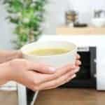 Woman holding bowl with tasty soup in kitchen