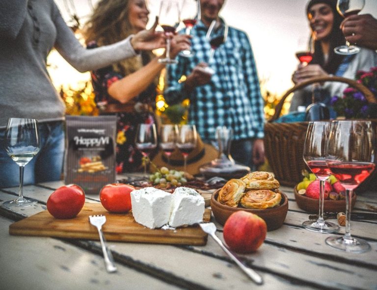 Una tavola tra amici per l'aperitivo al tramonto con vini rosati|Una bottiglia di vino rosso e tre calici su un tavolo||