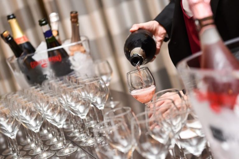 Lambrusco versato dalla bottiglia nei calici|Un piatto di carne e calice di lambrusco sfumato in primo piano