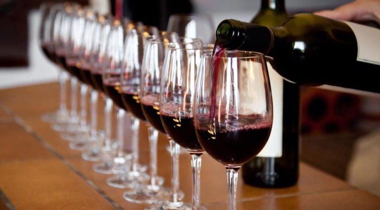 Calici allineati con vino rosso versato dalla bottiglia|Sala di degustazione per Bottiglie Aperte|
