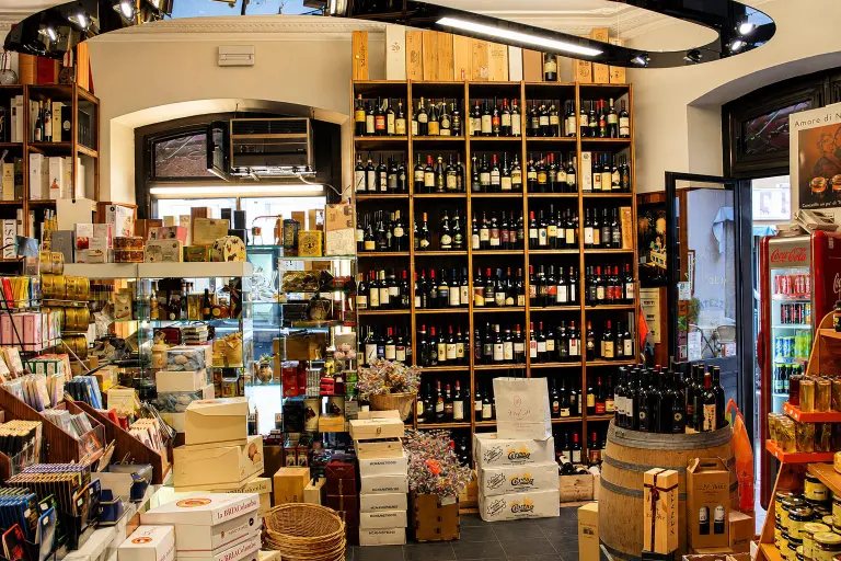 Scaffali dell'Enoteca Del Gatto ad Anzio con una vasta selezione di bottiglie di vino.