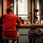 Persona sola seduta al tavolo di un ristorante mentre mangia da sola