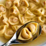 Tortellini bolognesi fatti a mano serviti nel brodo secondo la tradizione emiliana