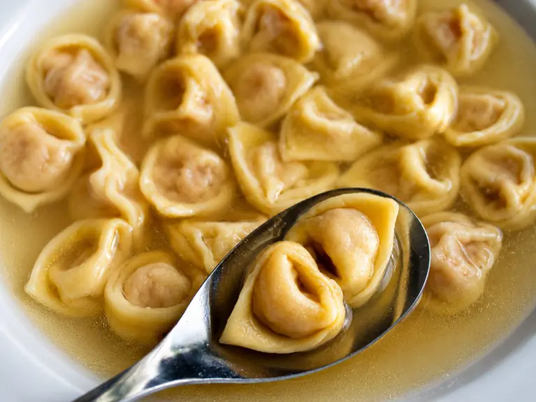 Tortellini bolognesi fatti a mano serviti nel brodo secondo la tradizione emiliana