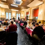Interno della trattoria San Filippo Neri a Milano con tavoli pieni, cucina milanese tradizionale e atmosfera popolare a Precotto