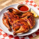 Pollo frango piri piri grigliato e glassato con salsa piccante servito su un piatto in Portogallo
